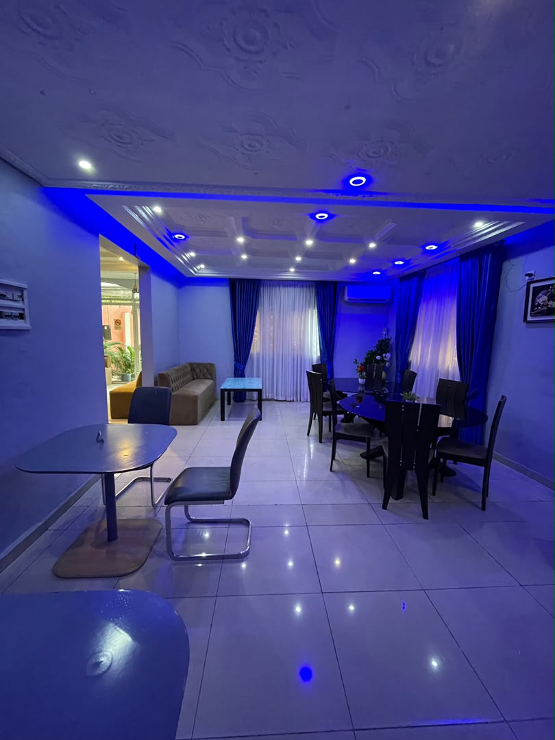 Salon intérieur du restaurant avec canapé et tables, baigné d'un éclairage bleu